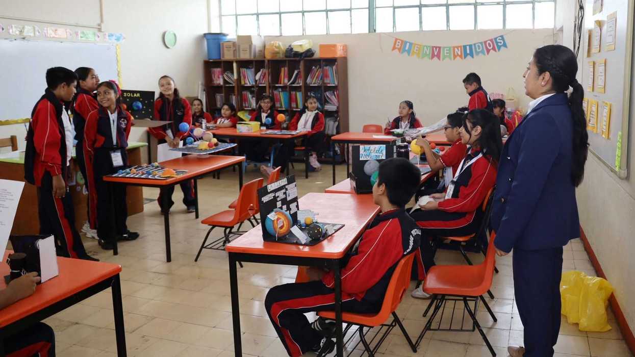 Students presenting models in a classroom with a teacher observing.