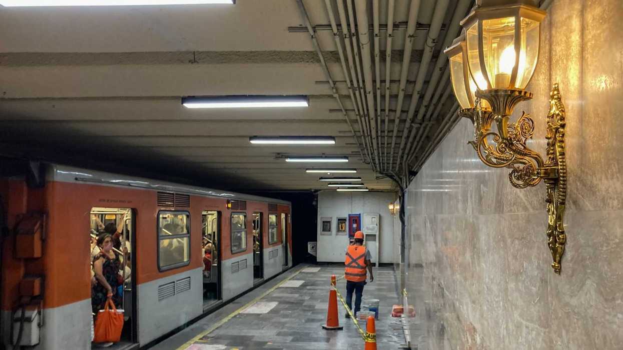 Subway platform with old lantern, barriers, and worker; passengers on train.