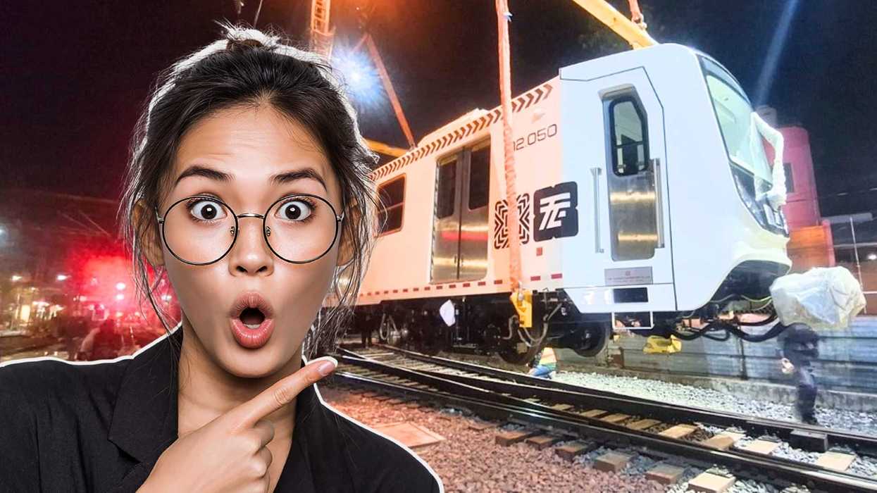 Surprised woman pointing at a train being lifted by cranes at night.