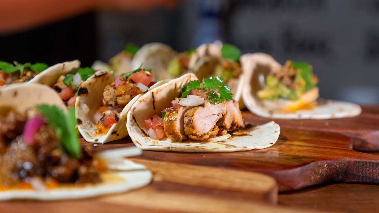 Tacos with various fillings on wooden boards, garnished with cilantro.