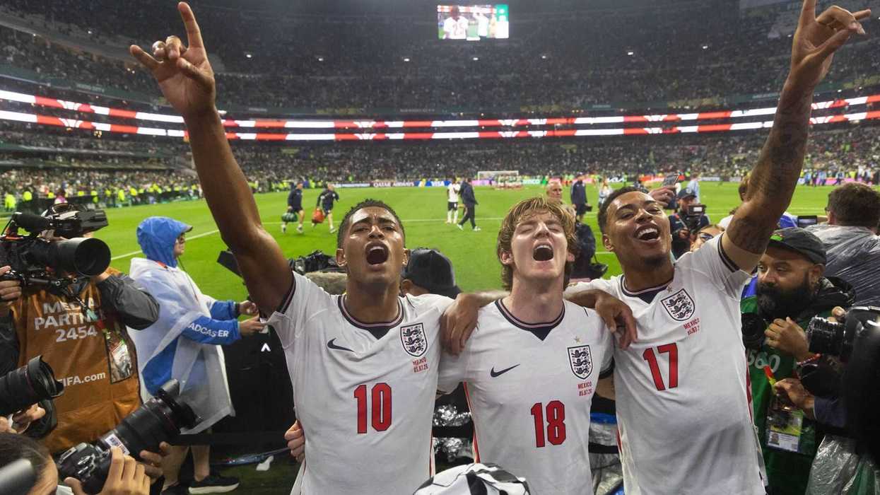 Three jubilant England soccer players celebrate on the field after a match.