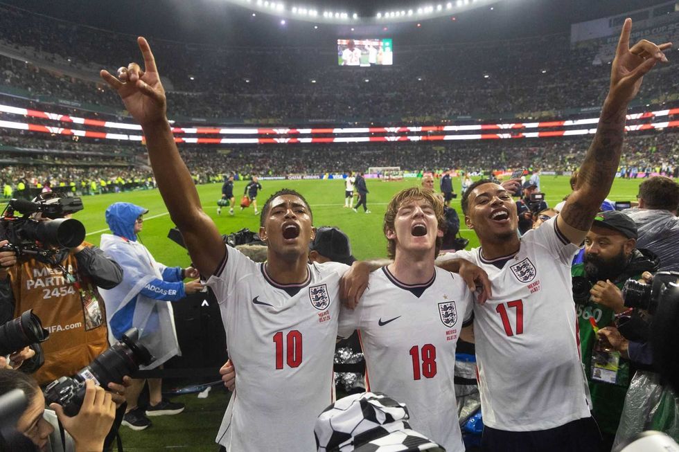 Three jubilant England soccer players celebrate on the field after a match.