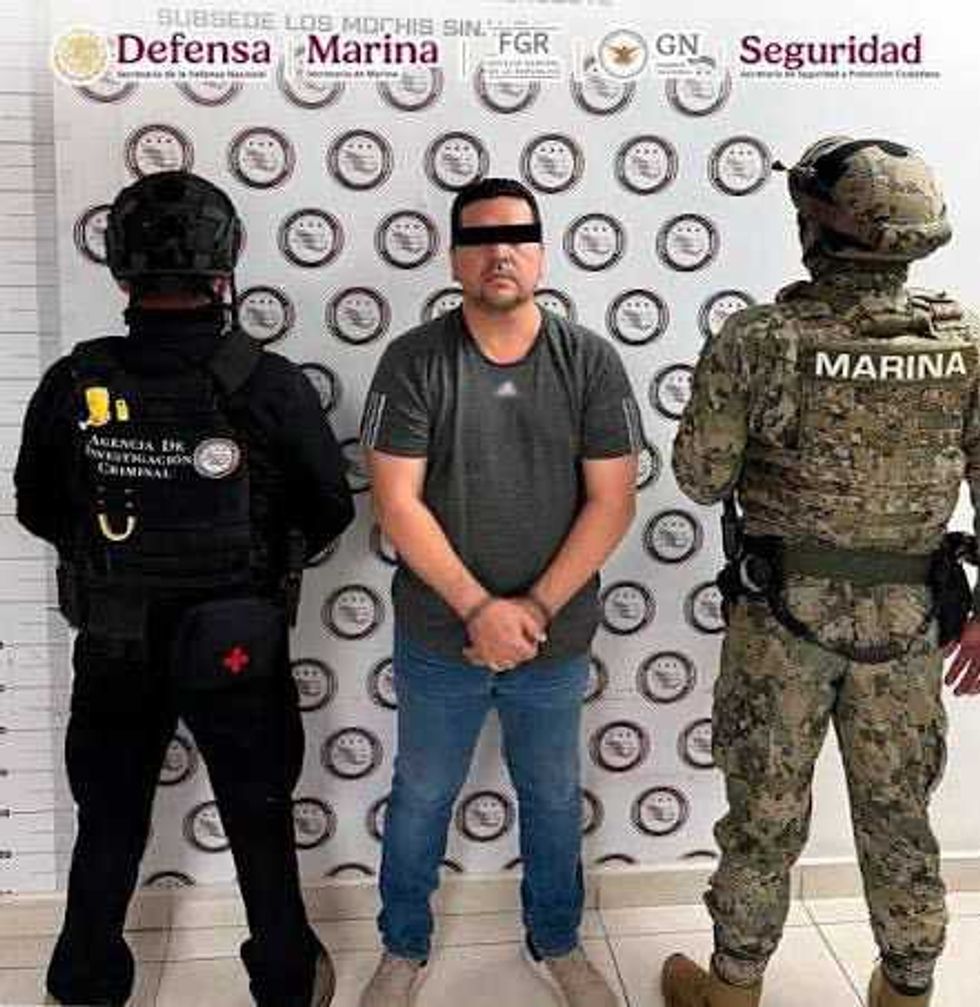 Three men: civilian handcuffed, flanked by law enforcement officers in tactical gear.