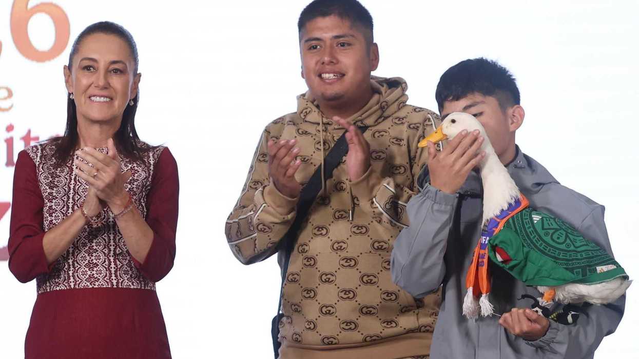 Three people applauding, one holding a duck in a green outfit.