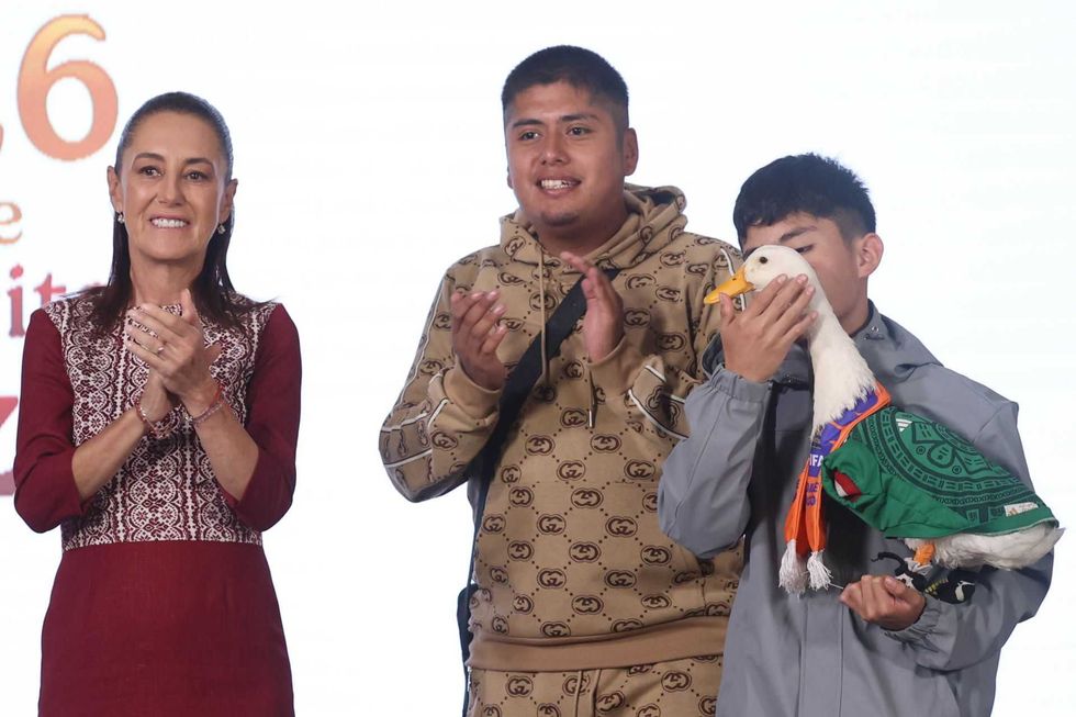Three people applauding, one holding a duck in a green outfit.