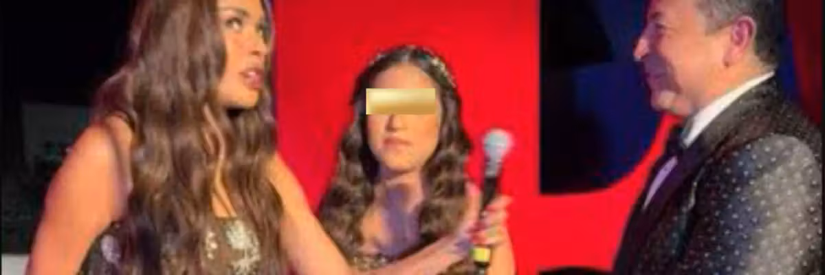 Three people on stage at an event, one holding a microphone, with colorful backdrop.