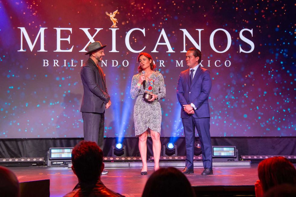 Three people on stage at the "Mexicanos Brillando por M\u00e9xico" event.