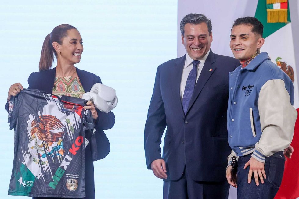 Three people smiling; one holds a Mexican-themed shirt and boxing gloves.