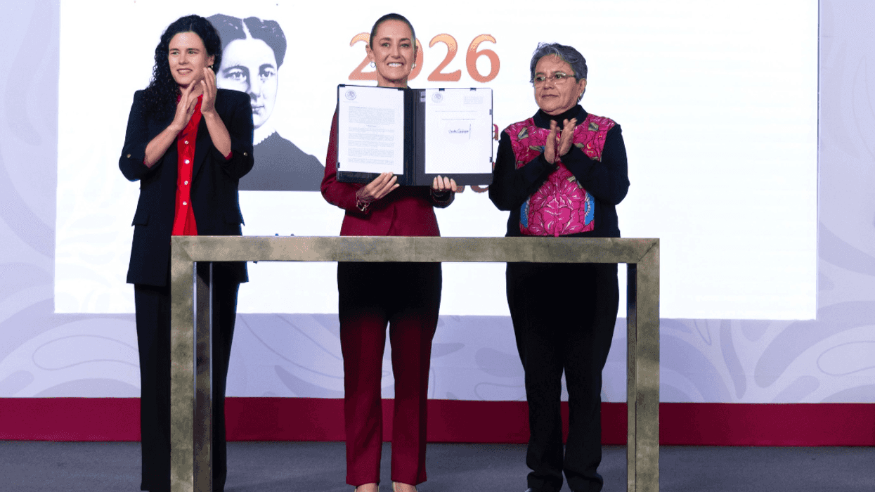 Three people stand on stage, one holding a document, with a 2026 backdrop.