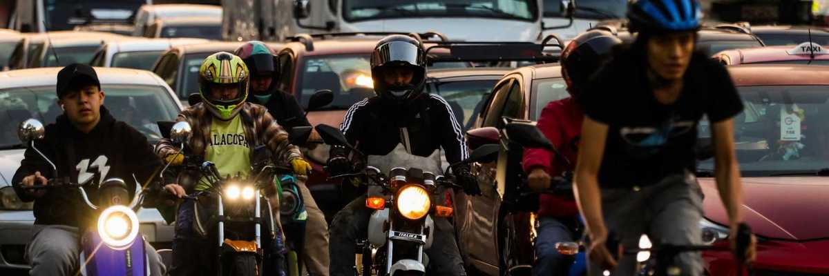 Traffic jam with motorbikes and cyclists maneuvering between cars and trucks.