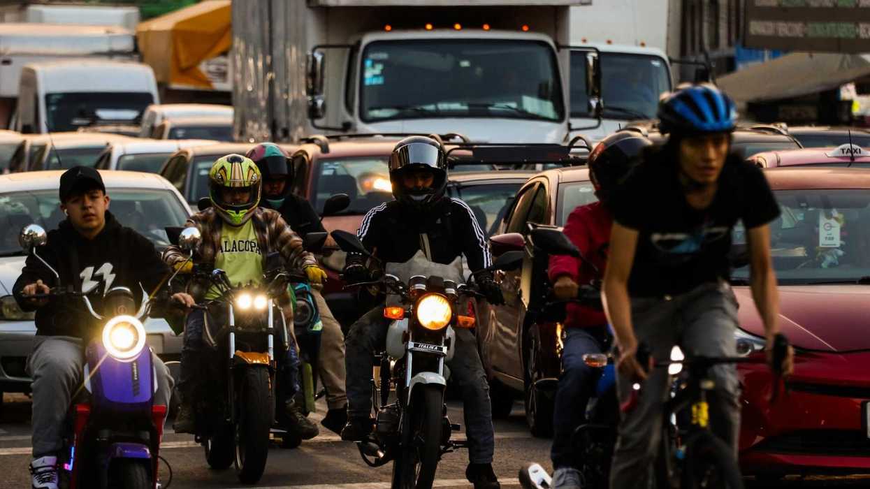 Traffic jam with motorbikes and cyclists maneuvering between cars and trucks.