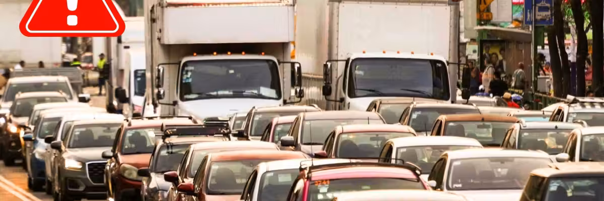 Traffic jam with trucks and cars, warning sign above.