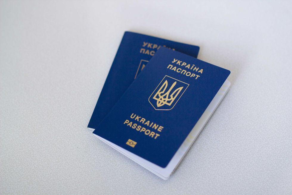 Two blue Ukrainian passports on a light surface.