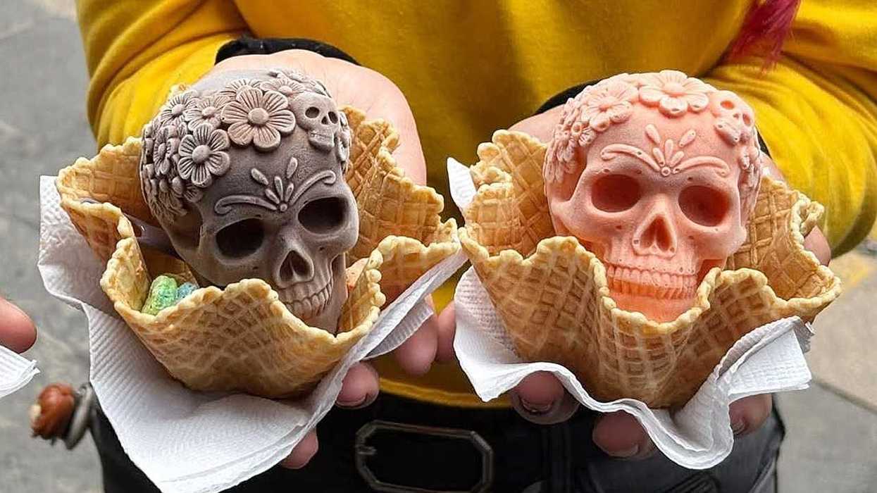 Two floral skull ice creams in waffle cones held in hands.