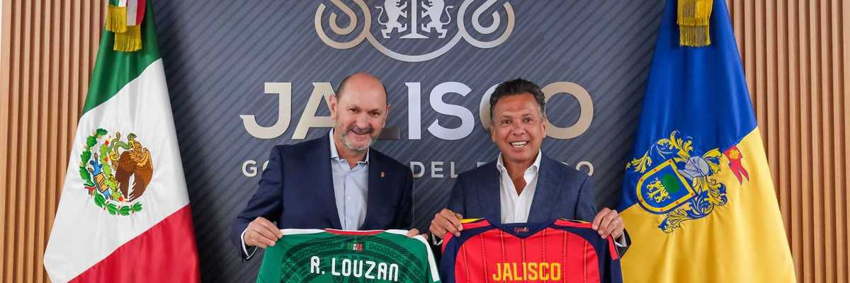Two men hold soccer jerseys in front of flags and a Jalisco emblem.