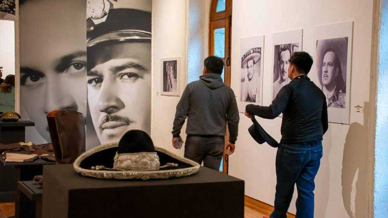 Two men view black-and-white film star photos in a museum exhibit.