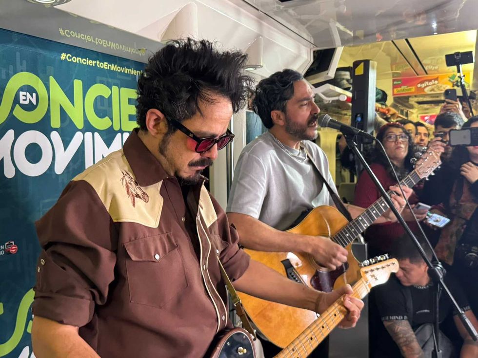 Two musicians play guitars and sing into a microphone at an intimate live performance.