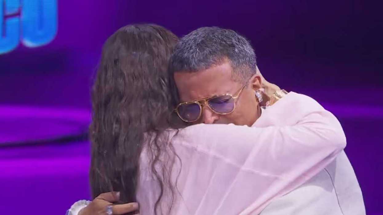 Two people embracing emotionally on a purple-lit stage.