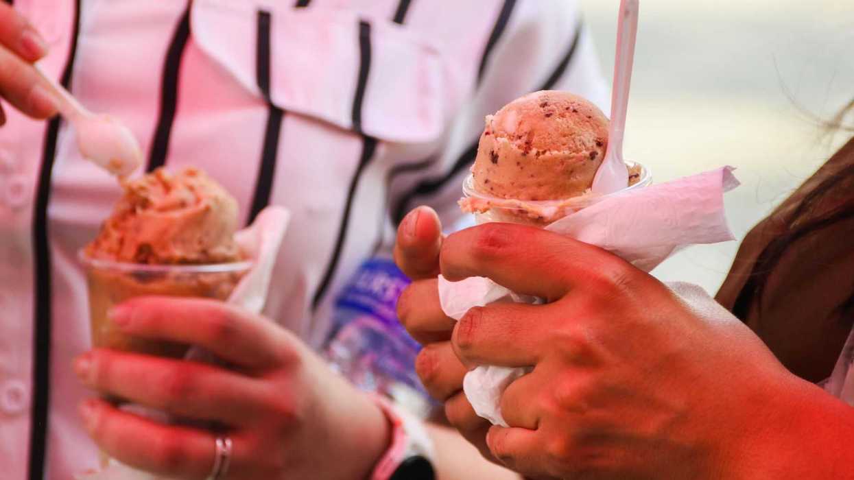 Two people holding cups of ice cream with spoons and napkins.