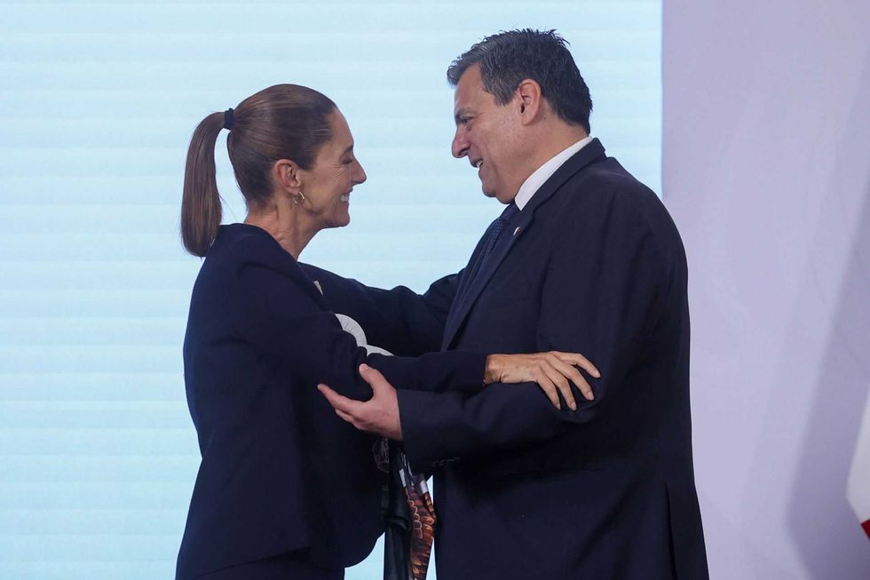 Two people in formal attire warmly embracing on stage.