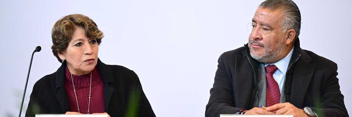 Two people seated at a table with microphones, engaged in conversation.