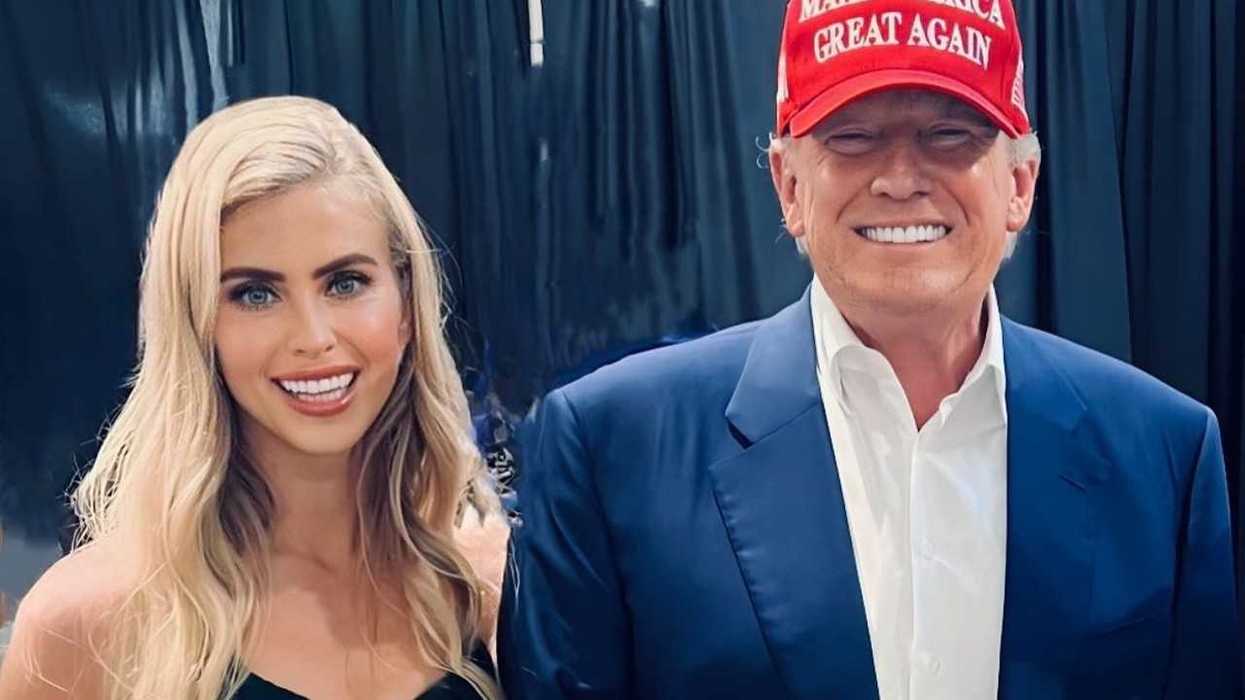 Two people smiling; one wears a red "Make America Great Again" cap.