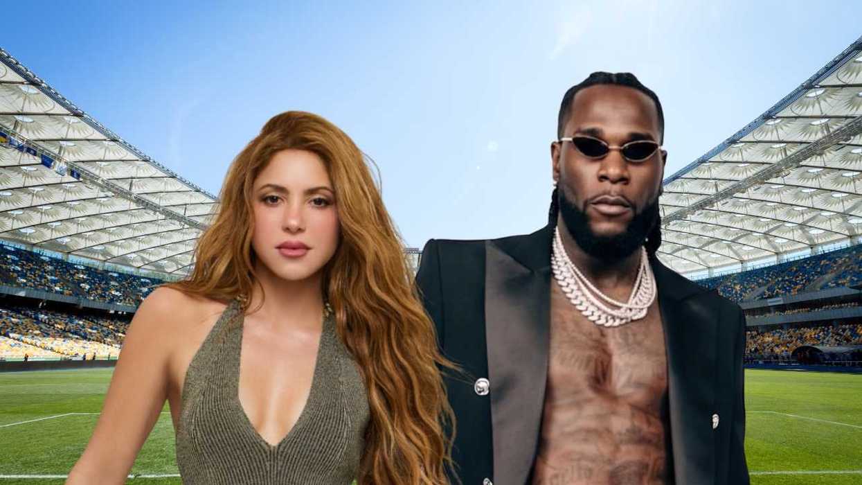 Two people standing in a stadium, one in a dress, the other in a suit jacket.