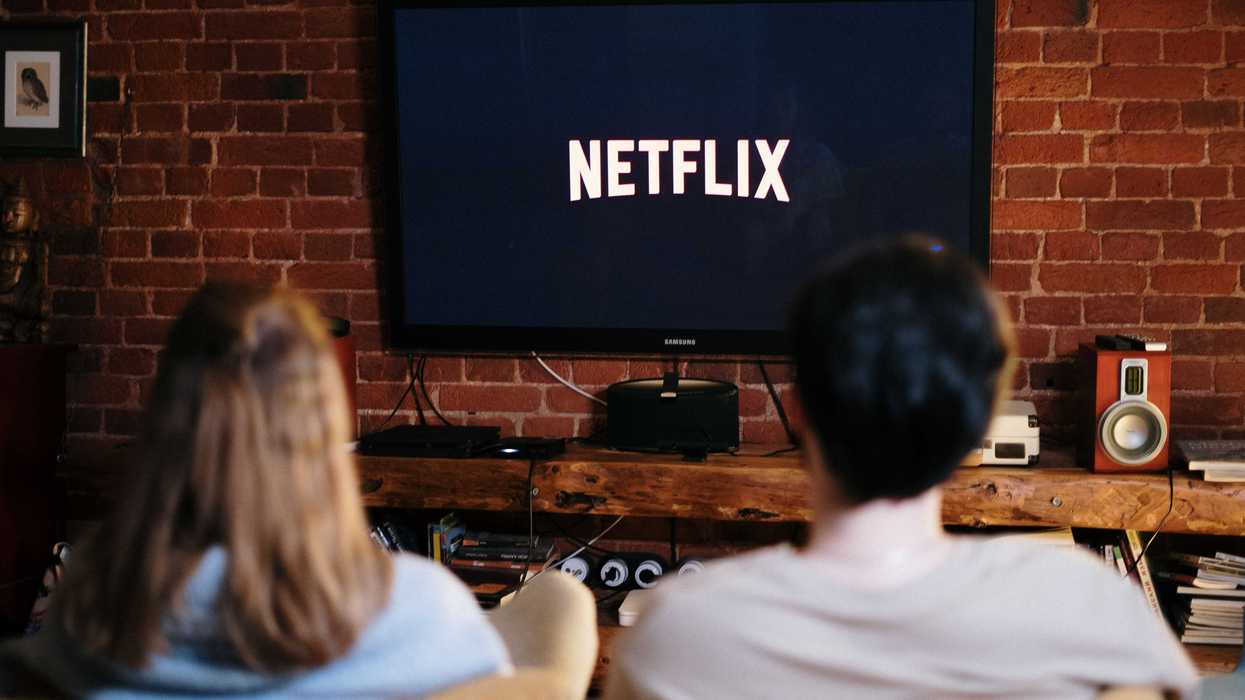 Two people watching Netflix on a TV in a cozy brick-walled room.