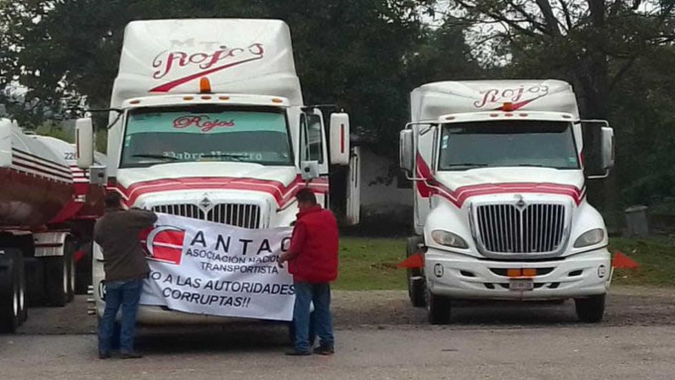Two semi-trucks with people holding a protest banner against corrupt authorities.