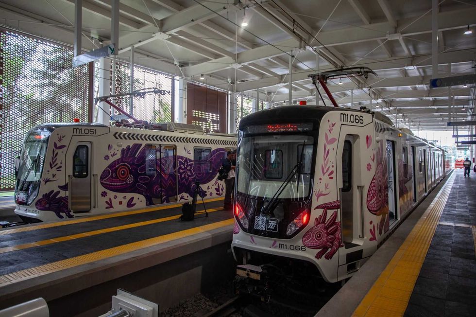 Two vibrant, art-covered trains at a modern, indoor station platform.