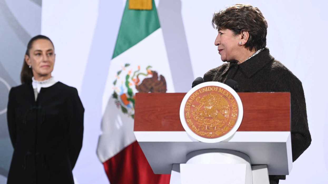 Two women at a podium, with a Mexican flag in the background.