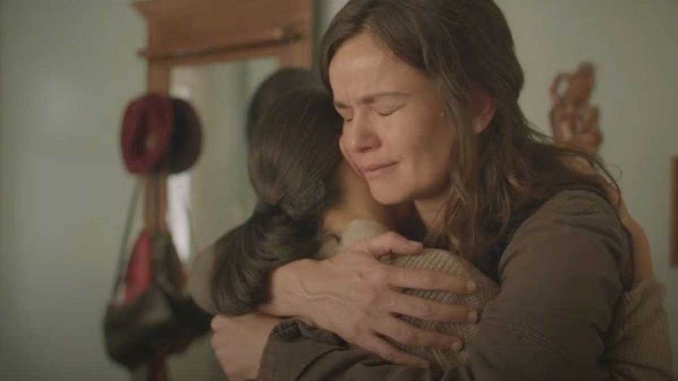 Two women embrace tightly, with one appearing emotional and tearful.