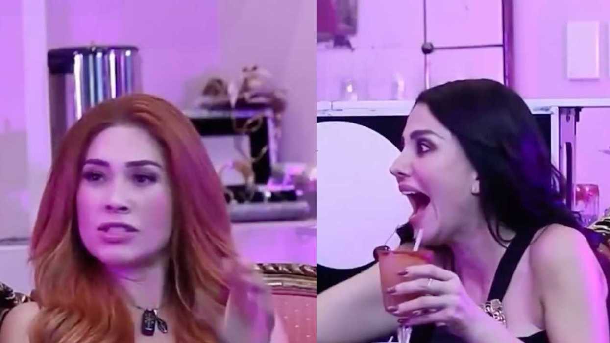 Two women in a purple-lit room, one looks surprised while the other gestures.