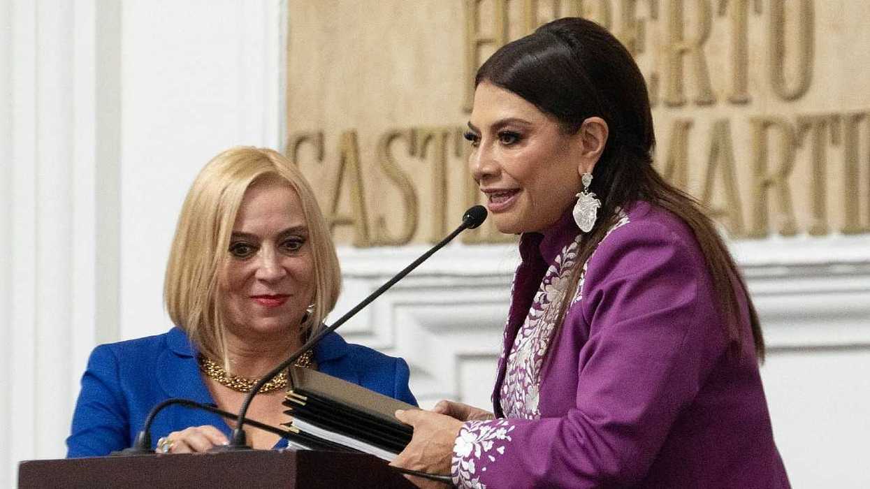 Two women standing at a podium during a formal event, holding a document.