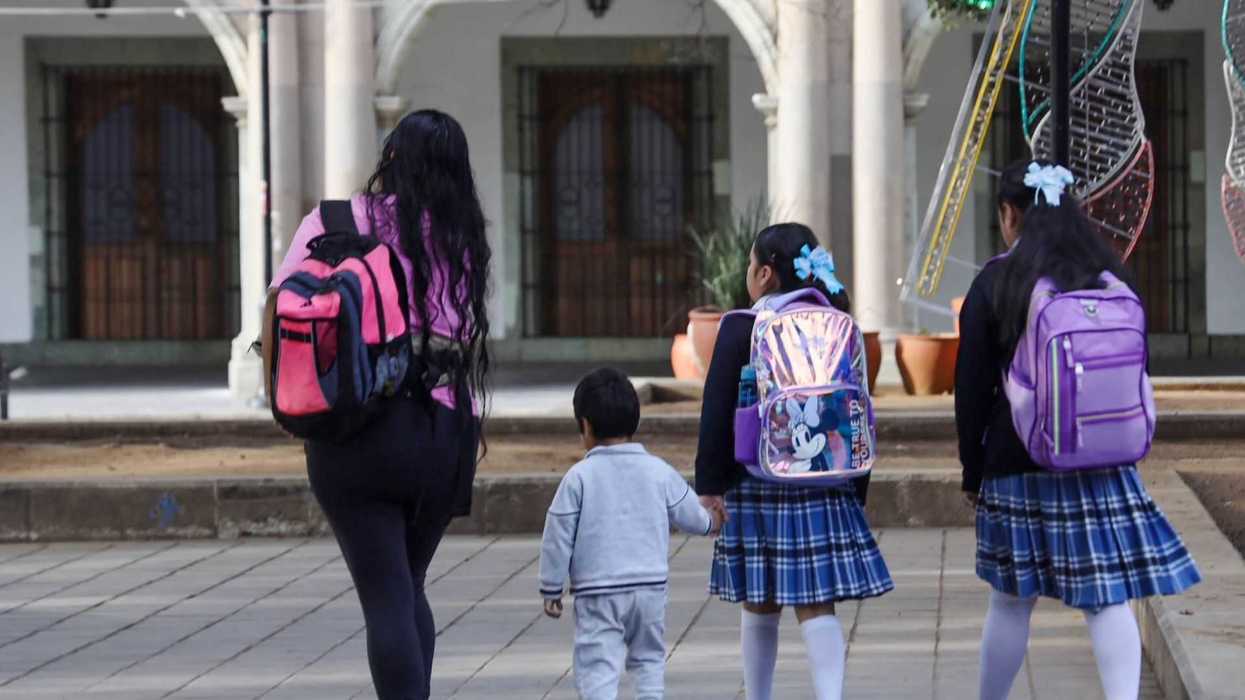 Un niño acompañando a sus hermanas a su escuela tras el regreso a clases