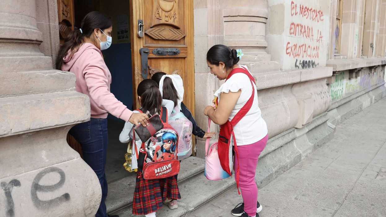 Una mamá lleva a la escuela a una de sus hijas