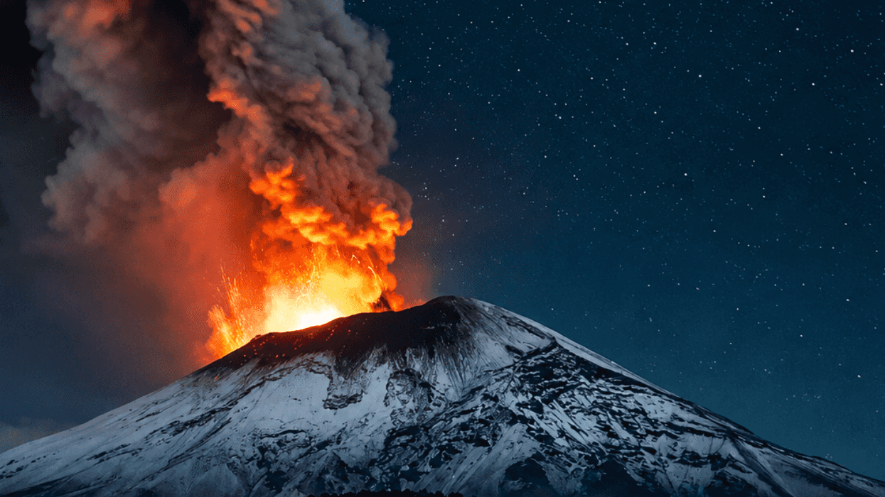 Volcano erupts at night, spewing lava and smoke under a starry sky.