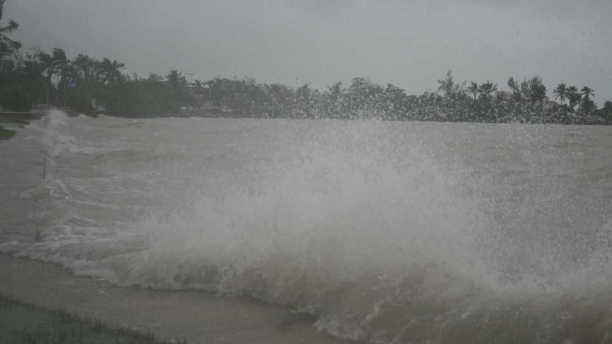 Waves crashing against a shore under a stormy, cloudy sky.