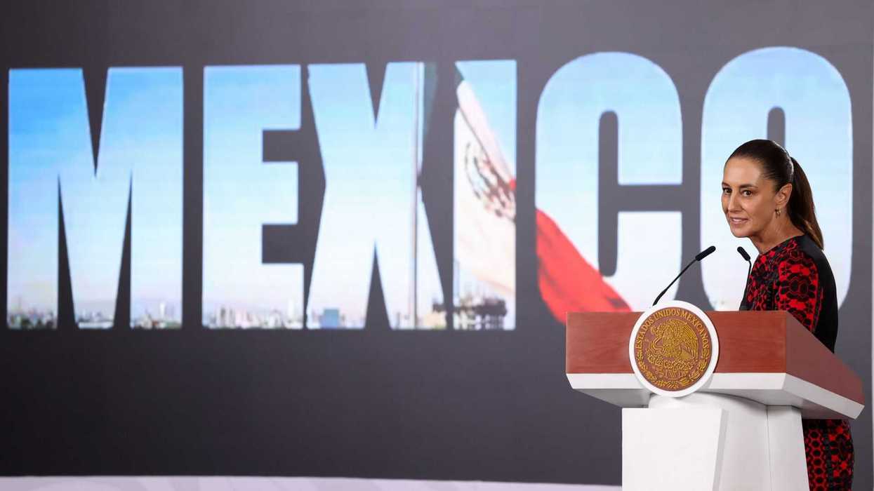 Woman at podium with "MEXICO" and flag backdrop.