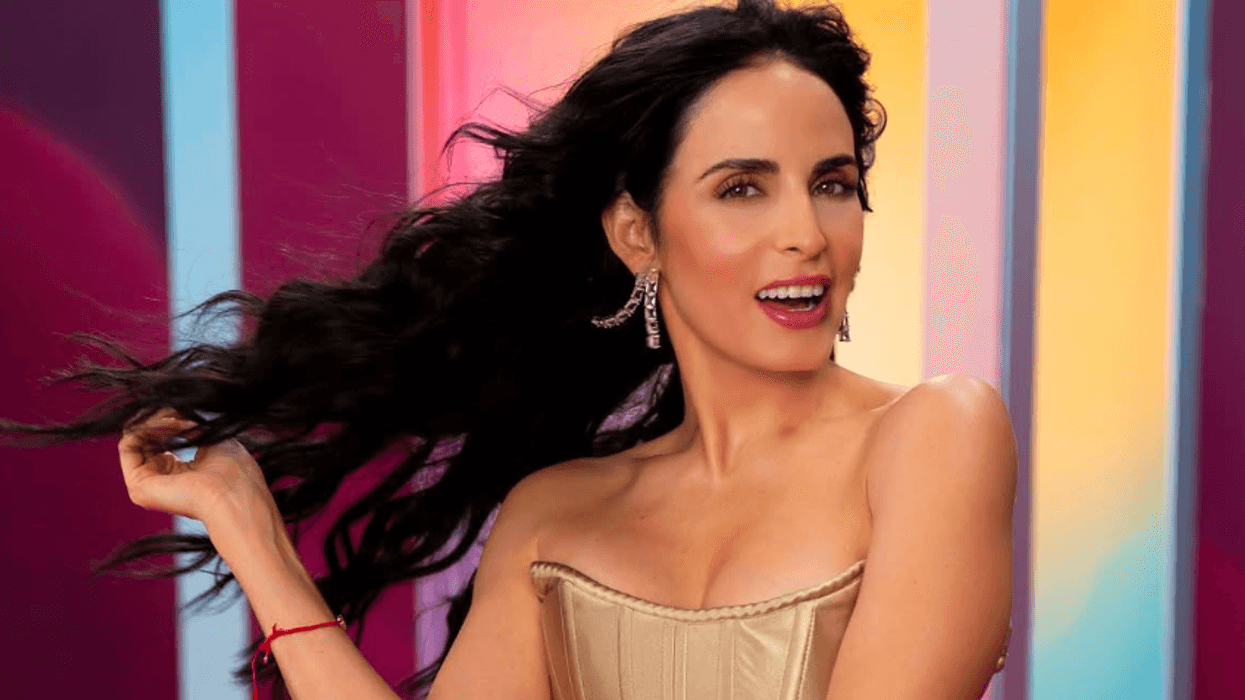Woman in a gold dress smiling, colorful striped background.