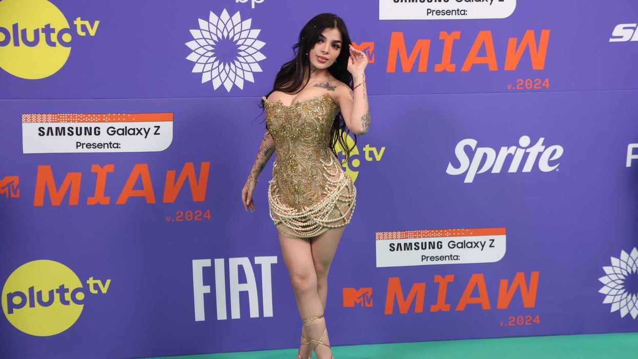 Woman in a gold embellished dress at the MTV MIAW 2024 event, sponsor logos behind.