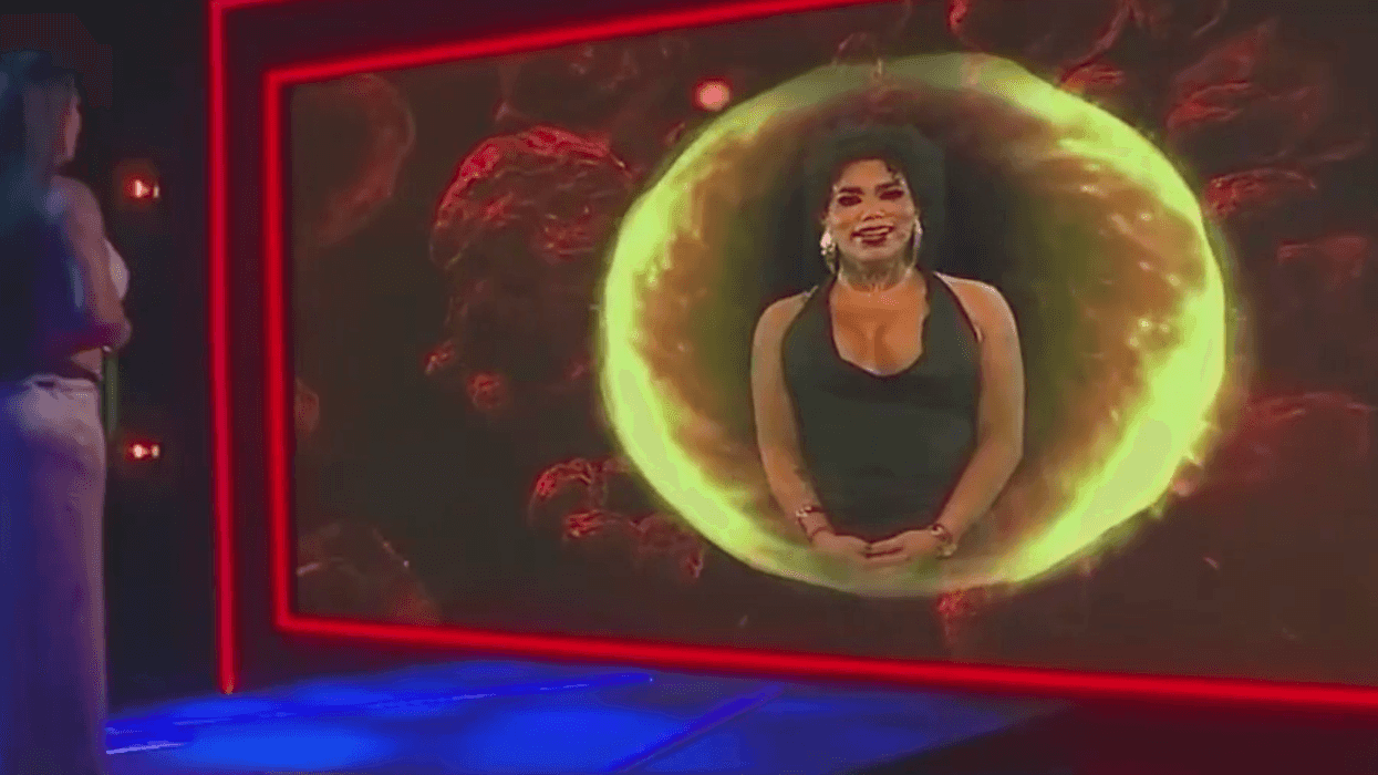 Woman in a white dress watches a holographic projection of another woman surrounded by light.