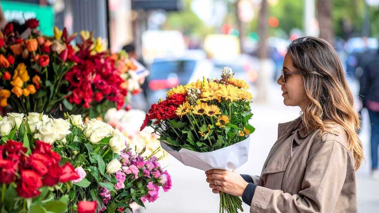 Woman in coat holding bouquet at flower shop.