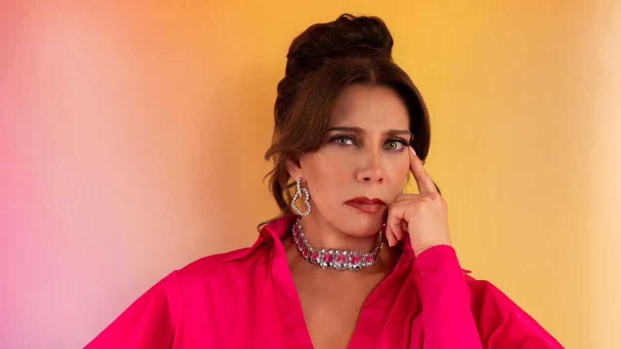 Woman in pink blouse and jewelry, thoughtful pose, colorful background.