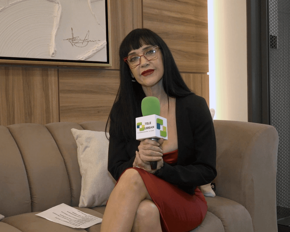 Woman in red dress holding a green microphone, sitting on a couch.