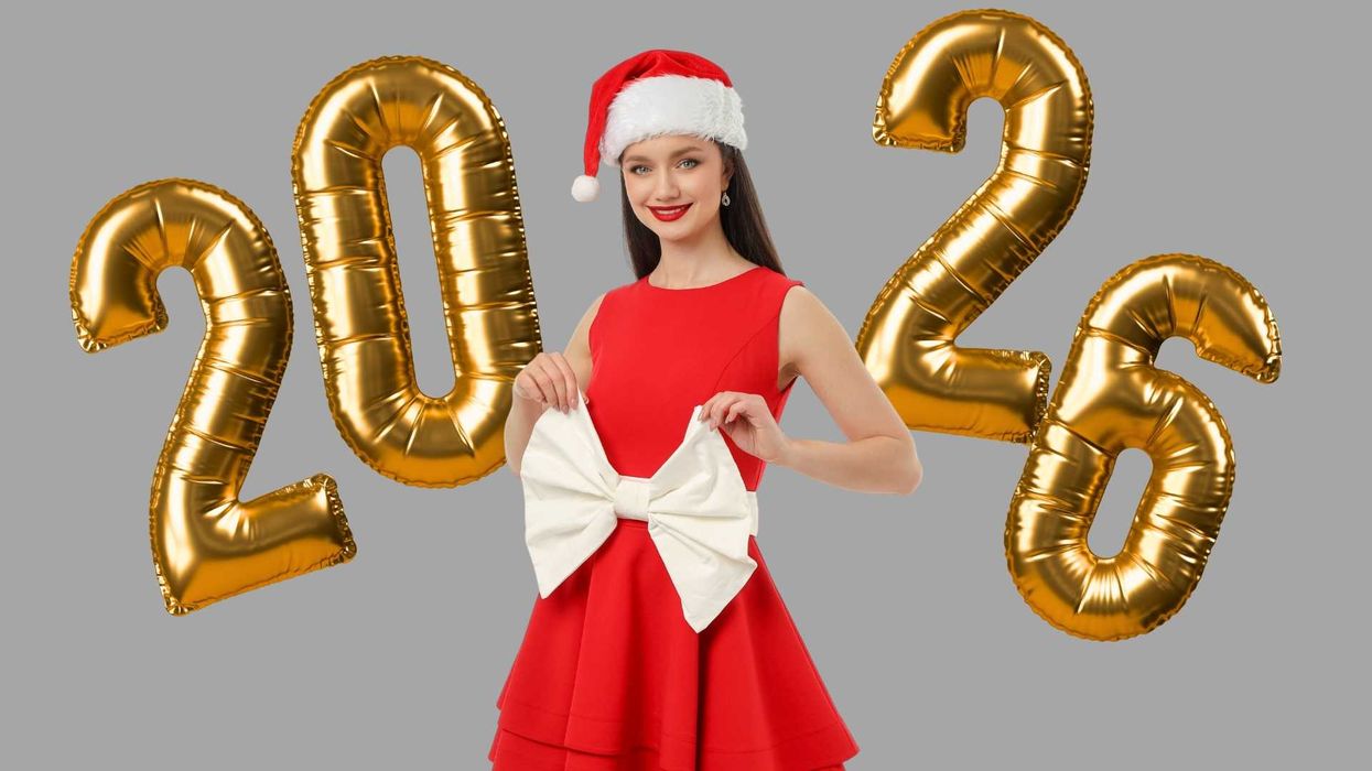 Woman in Santa hat with gold 2026 balloons on gray background.