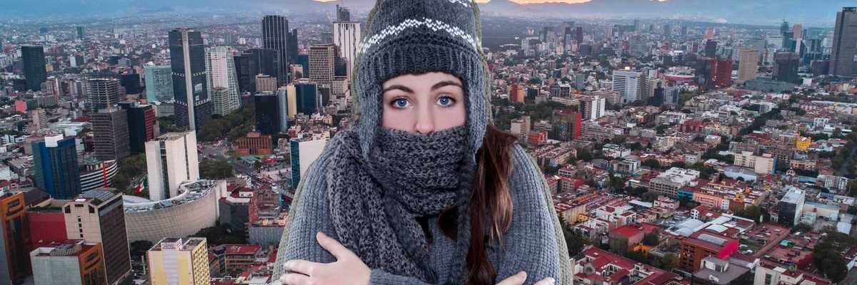 Woman in winter clothing against cityscape at sunset.
