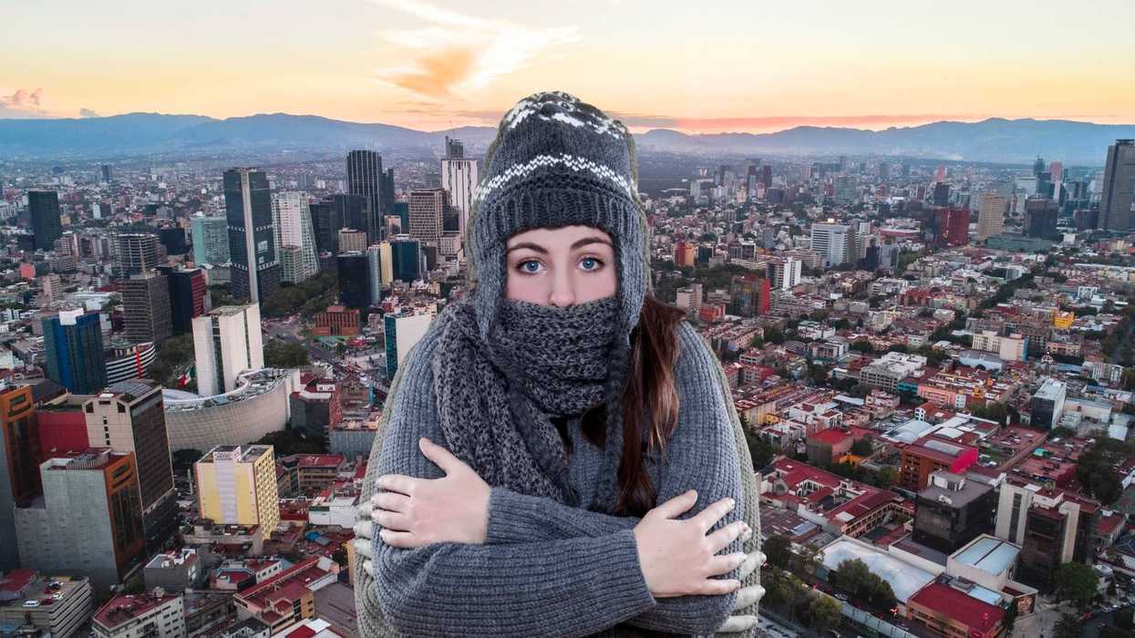 Woman in winter clothing against cityscape at sunset.