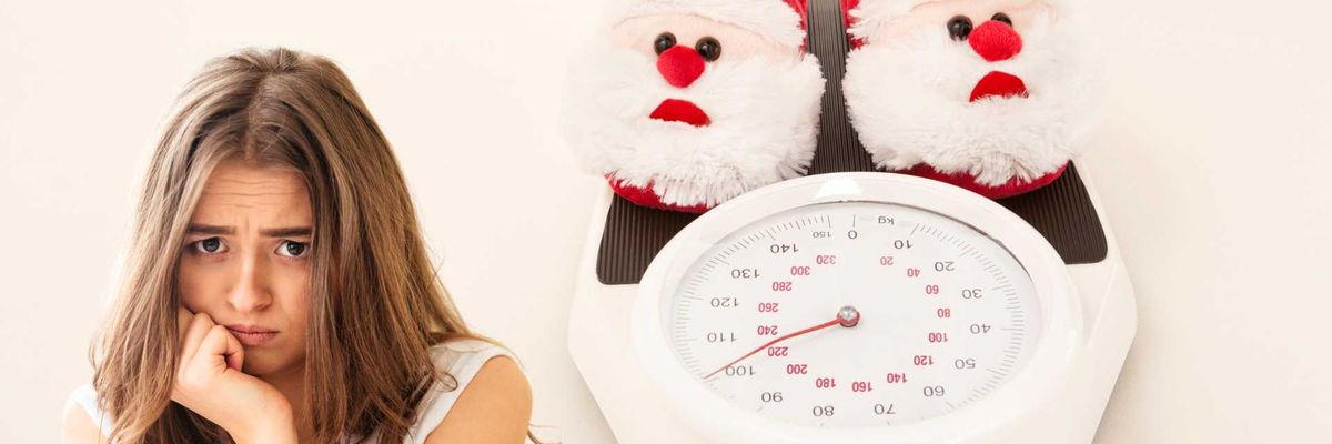 Woman looking worried beside scale with Santa slippers.
