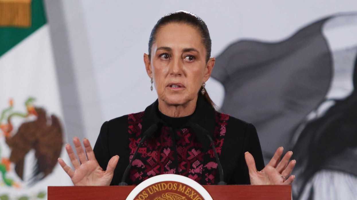 Woman speaking at a podium with a Mexican emblem, flag visible in the background.